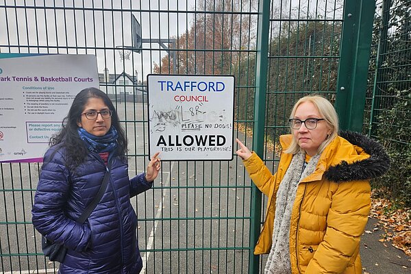 Cllrs Meena Minnis and Jane Brophy pointing at a sign with heavy graffiti